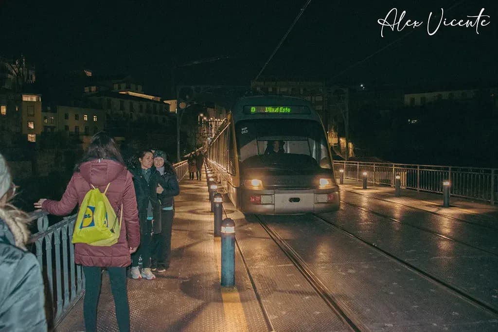 Tram and pedestrians crossing a bridge at night